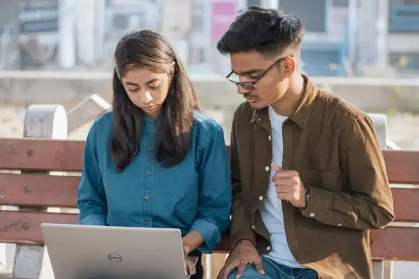 Two Indian students working together on a laptop on campus