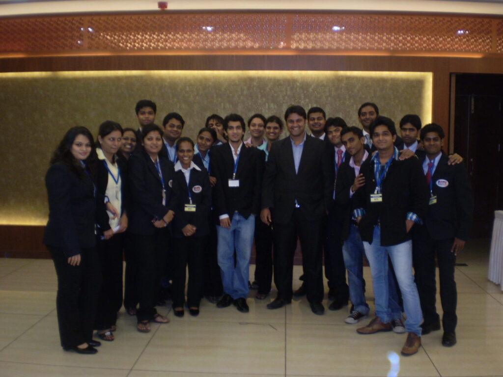 Group of ISMT student volunteers in dark blazers posing in a hotel lobby