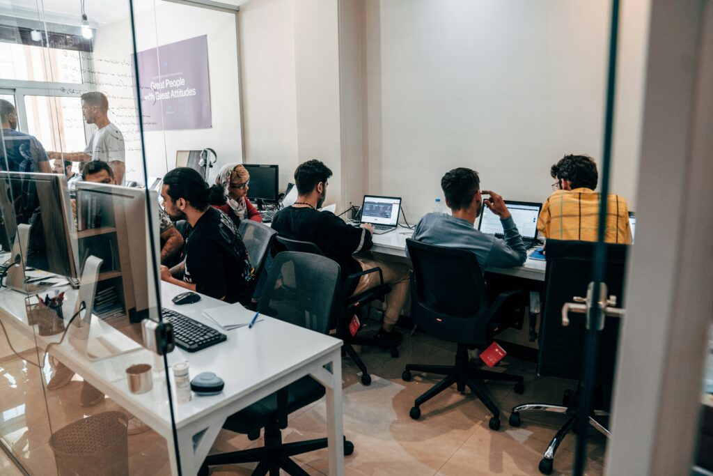 Group of recent BCA graduates or IT professionals working on laptops in a modern office, representing careers in software development and tech.